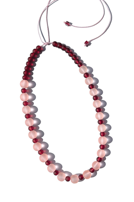 Beaded necklace with red and pink beads on a white background